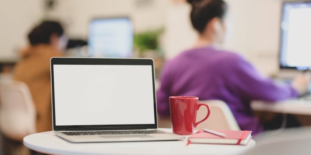 anonymous employees using computers in creative coworking space near laptop on table